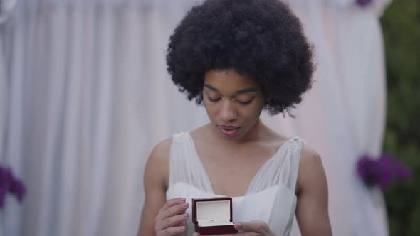 Portrait of Excited Young Woman in Wedding Dress Admiring Luxurious Wedding Rings in Box Looking at