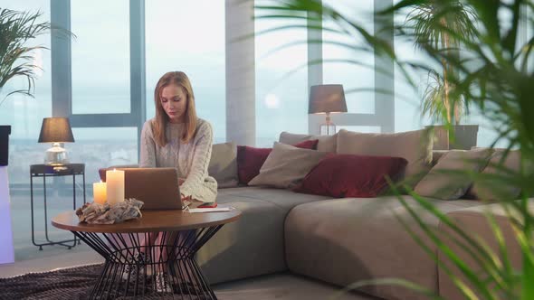 Pleasant Woman Sitting on Couch and Typing on Laptop