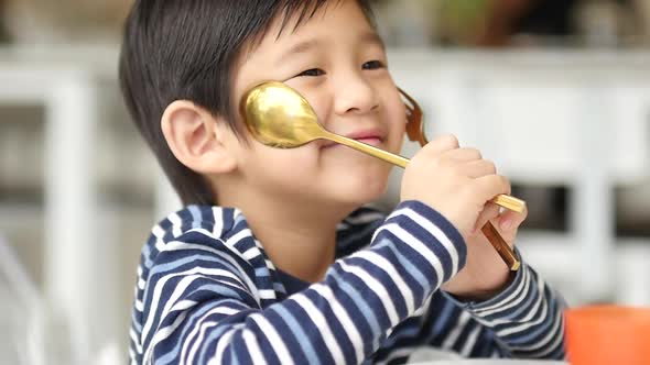 Cute Asian Child Holding A Spoon And Fork 