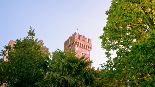 Top of Lazise Castle Seen Behind Green Trees on Sunny Day