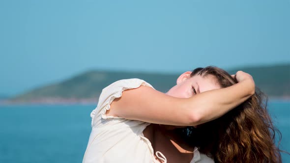 girl in a white sundress on the background of the sea on a bright sunny day