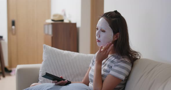 Woman apply face mask and watch TV at home