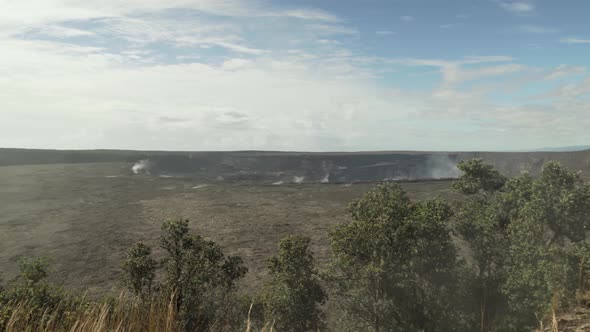 Right to left pan of volcano crater with heavy amounts of steam and smoke coming out of the ground a