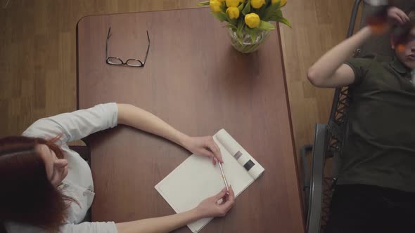 Relaxed Young Man Lying on a Cot in the Office of a Psychologist, Telling Her About His Problems