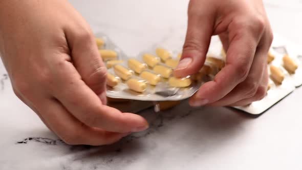 Female Hands Hold A Blister Pack With Oval Fish Oil Tablets