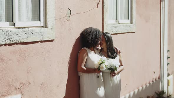 Lesbian Couple in Wedding Dresses Kissing and Hugging