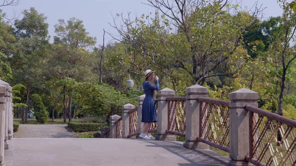 Smiling Woman on Vacation Staying and Relax on Bridge Over River