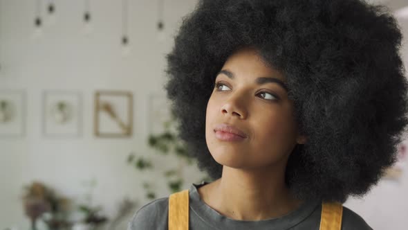 Confident African Woman with Afro Hair Looks at Camera Indoors Headshot