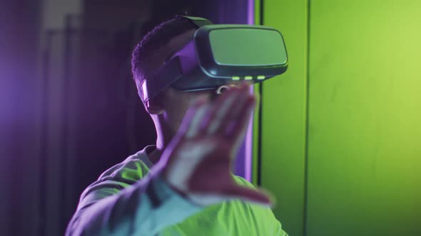 African american male computer technician using vr headset working in business server room