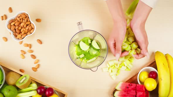 Putting Cut Celery Green Vegetables Into Blender with Apples Closeup