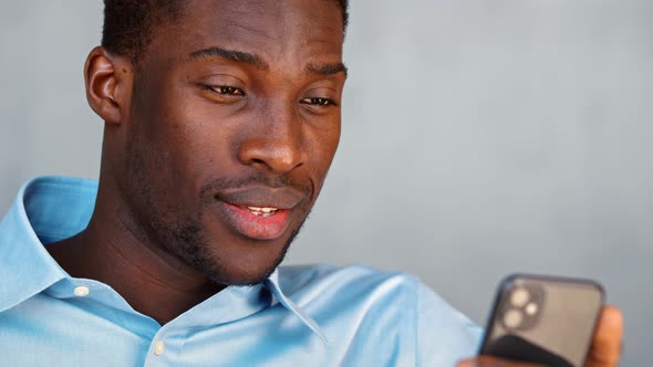 Smiling african american man talking on video call with friend using phone and internet