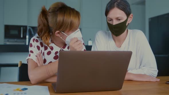 Two Young Women with Mask Working at Laptop Together During Epidemic Coronavirus