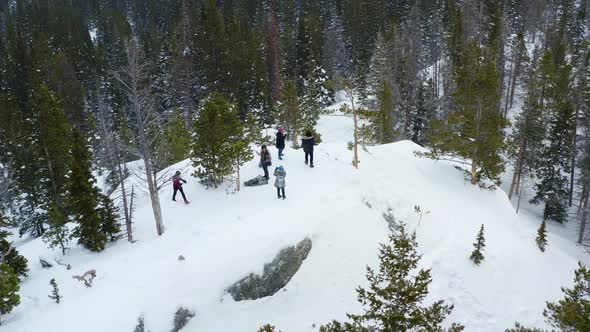 Aerial orbiting shot of a group of people on a snowy mountain
