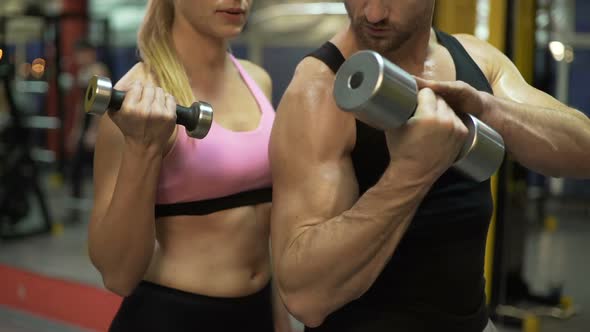 Couple Lifting Dumbbells Together in Gym, Guy Showing Correct Way to Do It