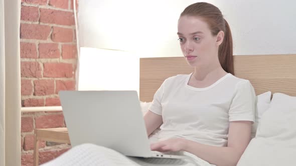 Ambitious Redhead Young Woman Working on Laptop in Bed