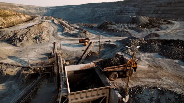 Quarry Dump Truck Unloads the Rock Into a Rock Crusher