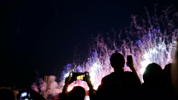 Crowd of People Watching Fireworks and Taking a Salute To the Smartphone. Beautiful Bright