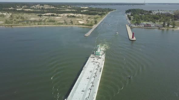 Aerial view of large freighter moving out of canal in Michigan, USA. Drone circles slowly to the lef