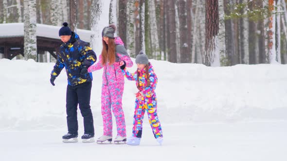 Family with Little Daughter Skates About Open Rink in Park