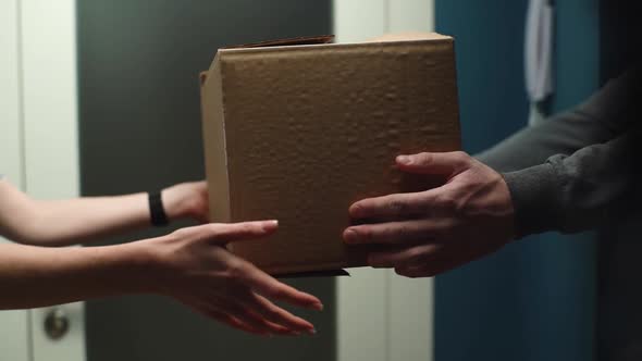 Closeup View of Woman Receiving Parcel at Home From Delivery Man Hands on Doorstep at Apartment