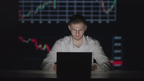 Young Caucasian Man Trader Working at Monitor Laptop and Browsing Online in Trading Office