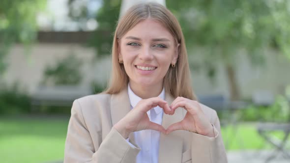 Outdoor Portrait of Young Businesswoman Making Heart Shape with Hands