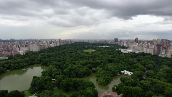Aerial view overlooking The Central Park Lake, in cloudy NYC, USA - tilt, drone shot