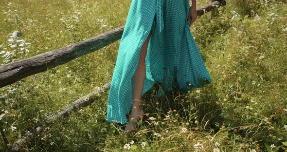 Girl Barefoot In A Long Dress Walking On The Grass