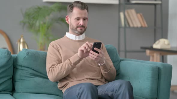 Man Using Smartphone on Sofa