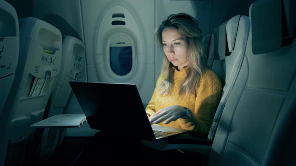 A Woman Is Using a Laptop on the Airplane. Female Passenger Working Inside of an Airplane.