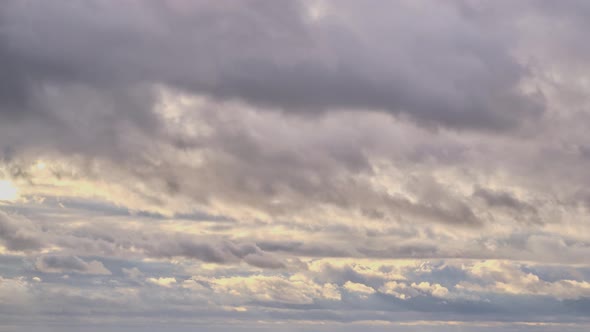 Dark rain clouds in the red light of the setting sun, time-lapse sunset