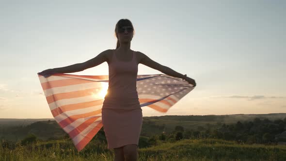 Happy woman with USA national flag outdoors at sunset.