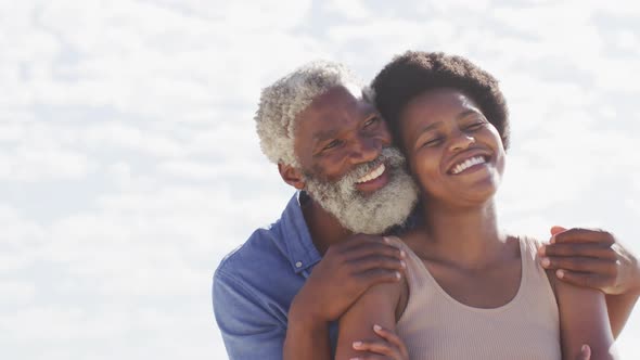 African american couple embracing and looking away on sunny beach