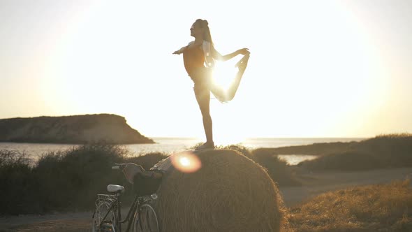 Wide Shot Flexible Fit Caucasian Young Woman Raising Leg in Sunrays in Slow Motion Standing on