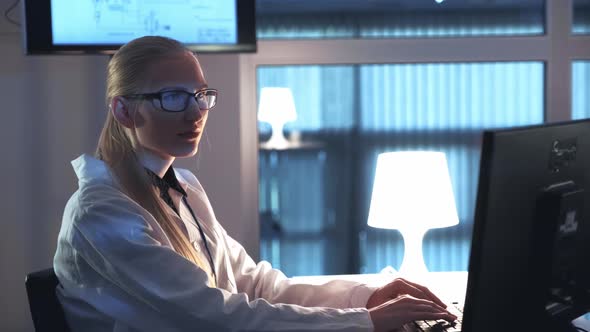 Female Electronics Engineer Working on the Computer and Writing the Results of the Research in