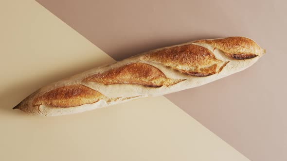 Video of one baguette on a brown and beige surface