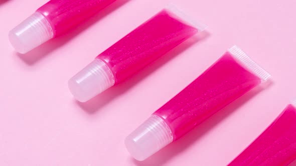 Lot of homemade lip glosses on pink background