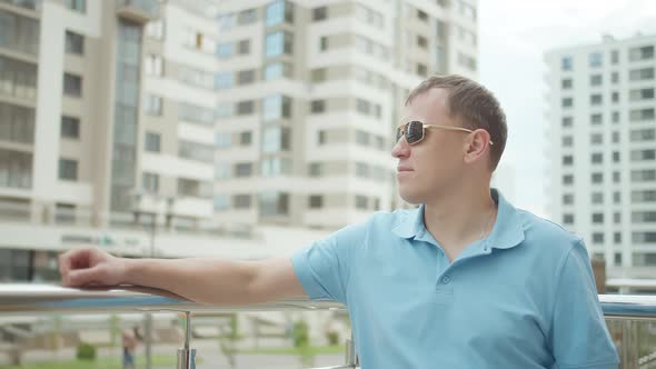 Man in Sunglasses Stands Near Metal Railing