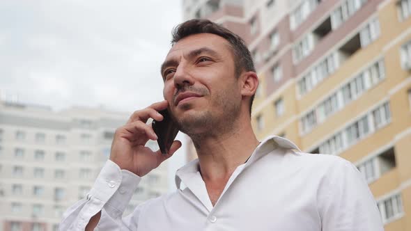 Handsome Businessman Speaks on the Phone with a Smile