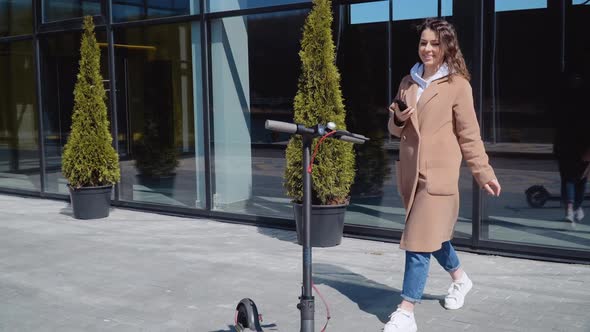 A Young Girl Rents Electric Scooter Using Mobile Phone App