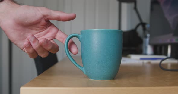 Coffee cup sitting on a desk being moved by hand