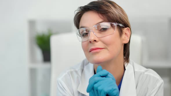 Closeup Face of Smiling Beautiful Mature Woman Scientist in Safety Glasses White Coat and Gloves