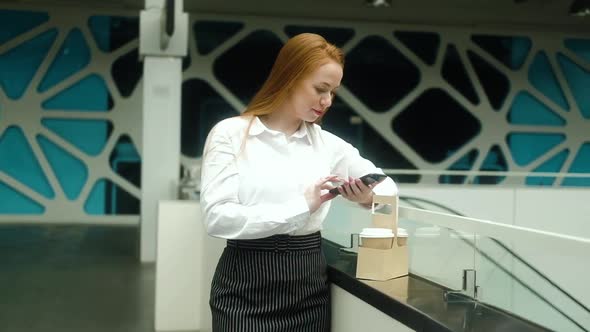 business woman with a cup of coffee uses the phone in the office