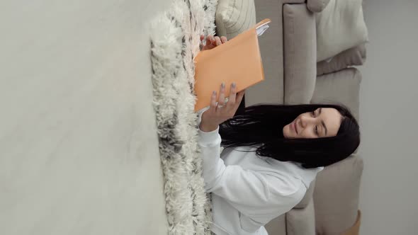 Young Woman Reading a Book Lying on the Floor in a Comfortable Living Room, Reading Books. Stay Home