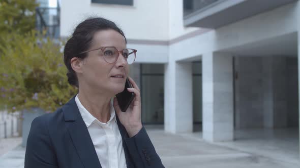 Serious Businesswoman in Office Suit Talking on Mobile Phone