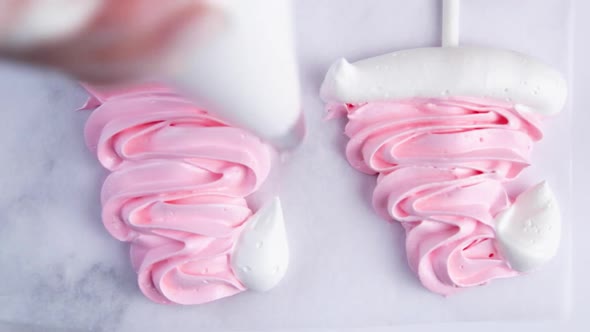 On Light Parchment There are Pink Meringue Caps on Sticks the Cook Makes a Pompom and a Frill From a