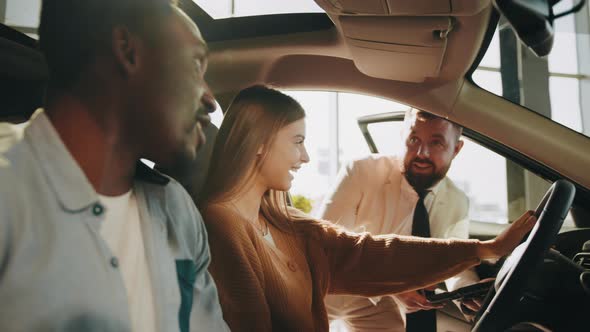 Happy Multi Ethnic Couple Sitting Inside Modern Auto While Talking with