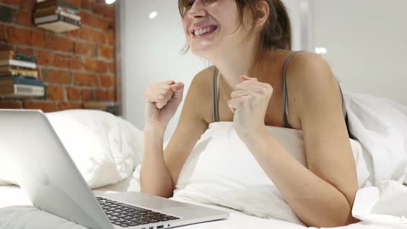 Happy Woman in Bed Working on Laptop and Reacting to Success,