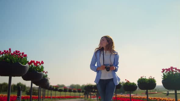 Happy Female Photographer Running in Slow Motion in Blooming Park in Sunny Day