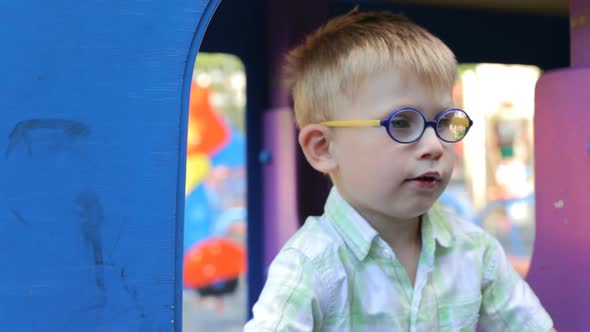 A little boy is played on the playground in a toy car.